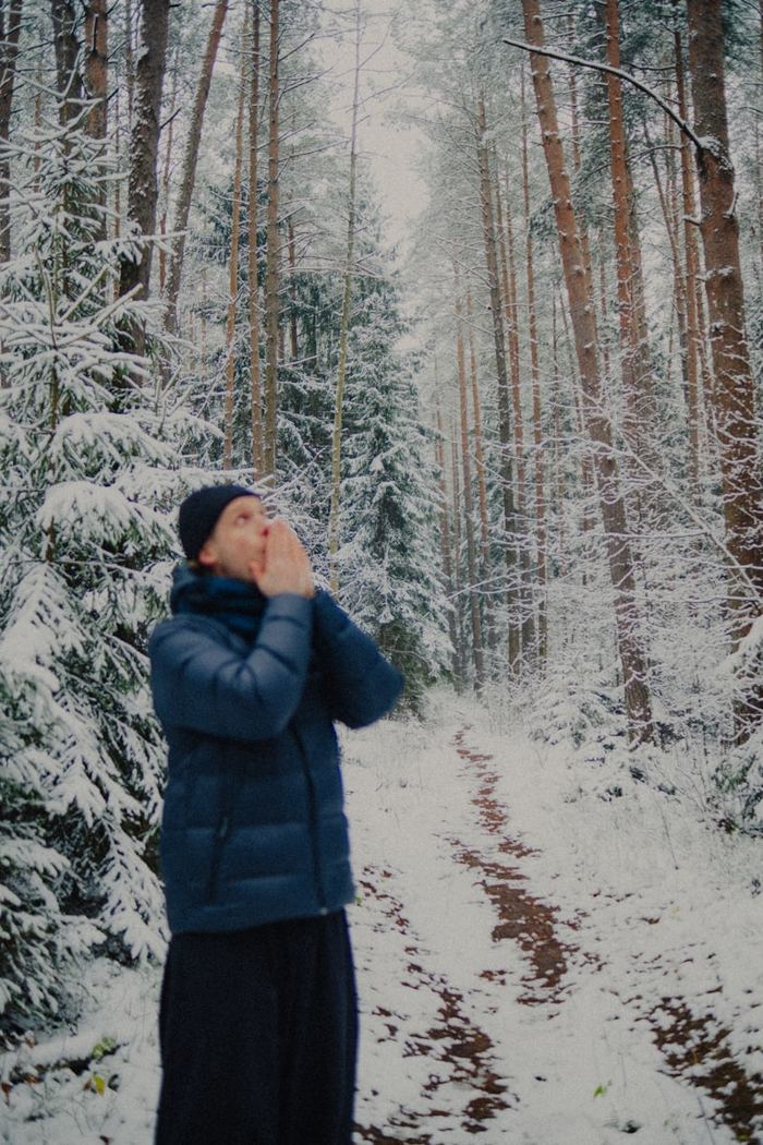 Pessoa aquecendo as mãos numa floresta com neve